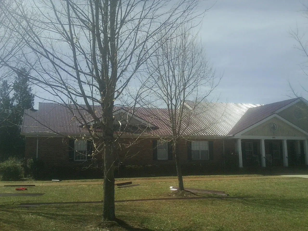 Red metal roof on a brick building seen from the front lawn in Sagle