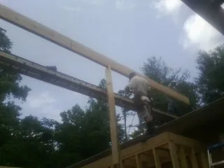 Carpenter setting a ridge beam over a new addition frame — Ice Dam Removal by Roofing Brothers in Sagle