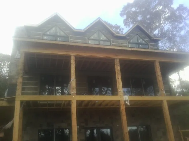 Dormers and porch framing on a large log home under construction — Roof Coating work by our crew in Sagle