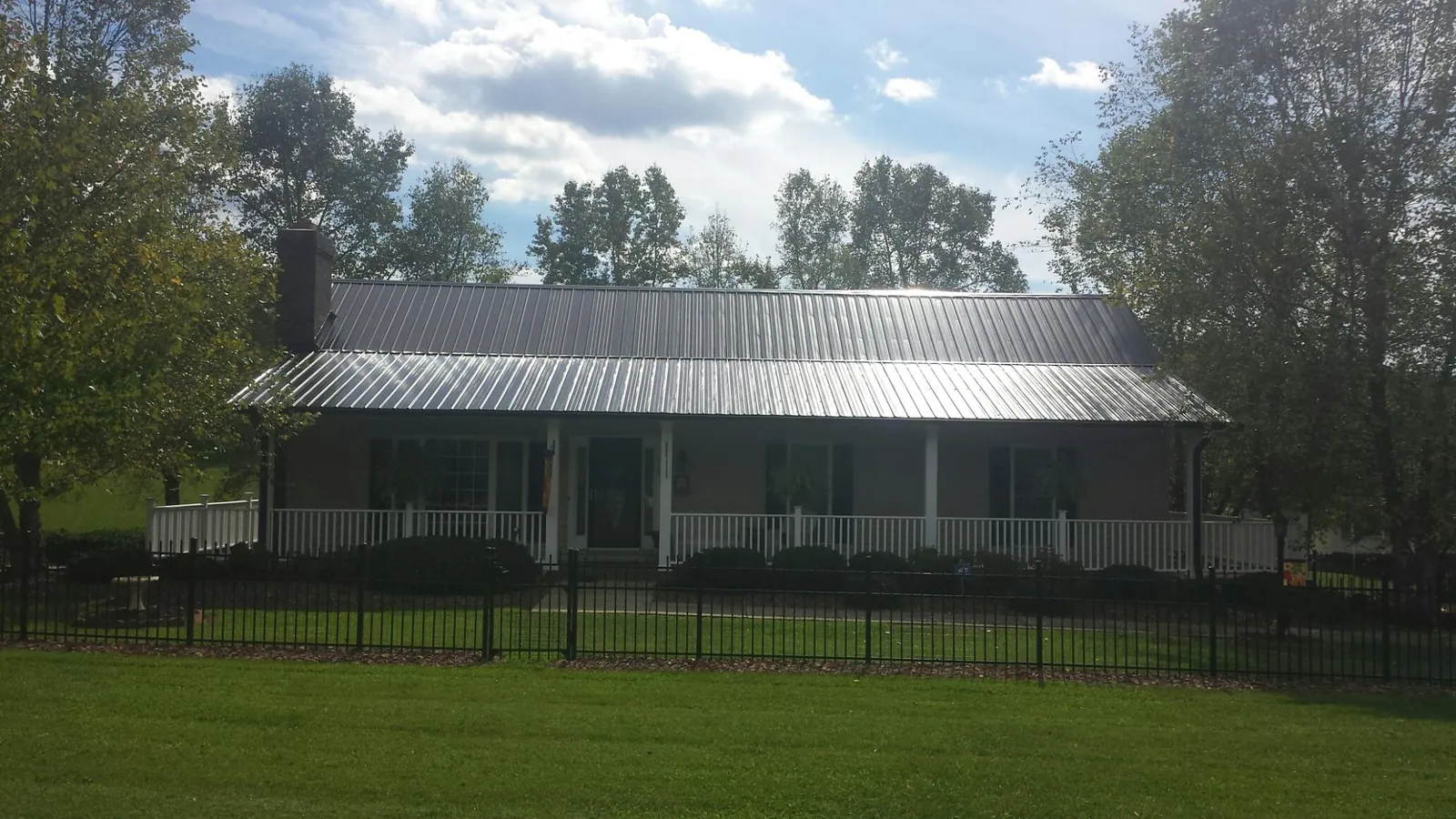Gray metal roof on a brick ranch with a full width front porch — Gutter Guard Installation work by our crew in Sagle