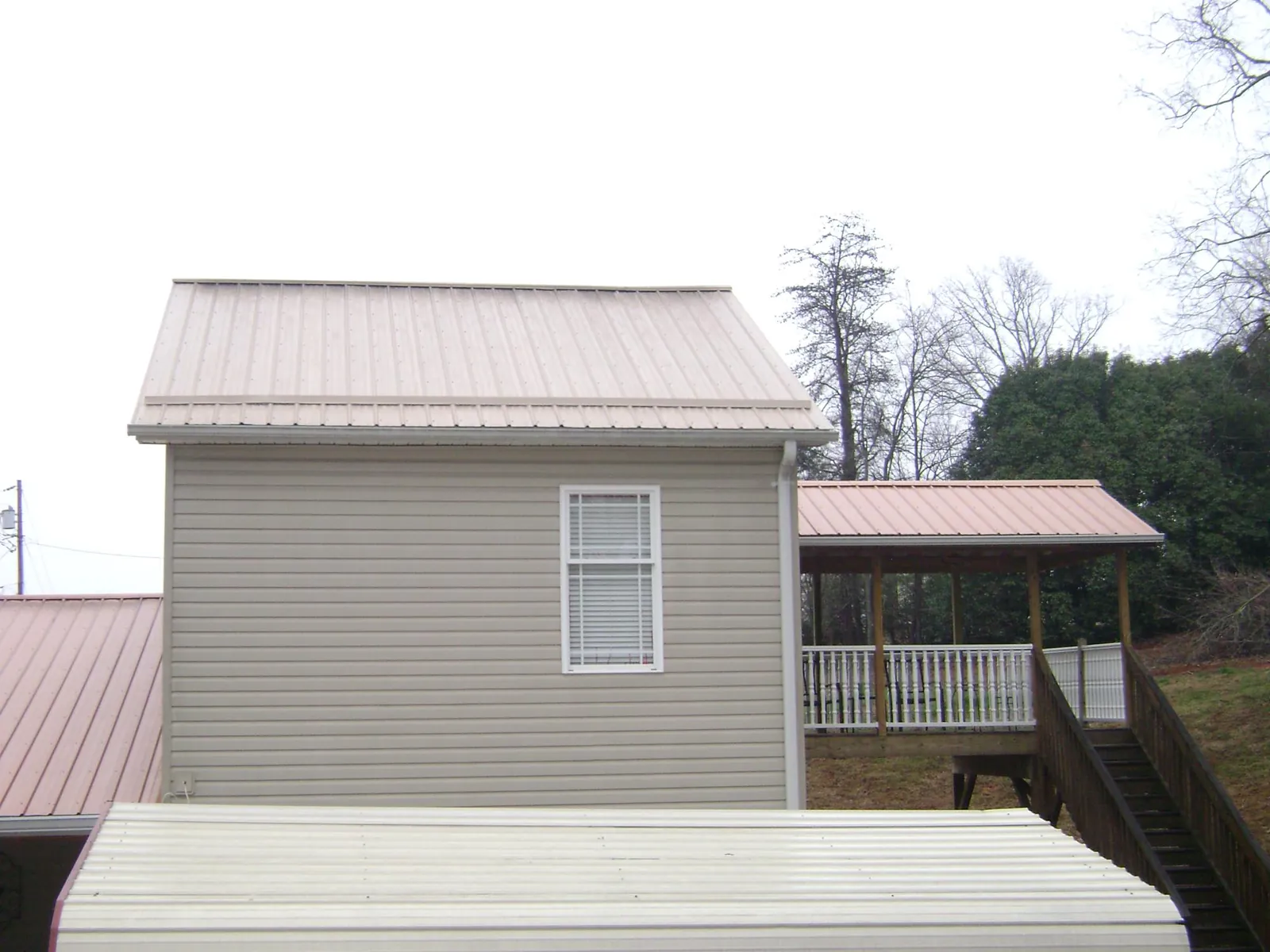 Tan metal roofs on a two story addition and attached porch, from a Roof Replacement job in Sagle