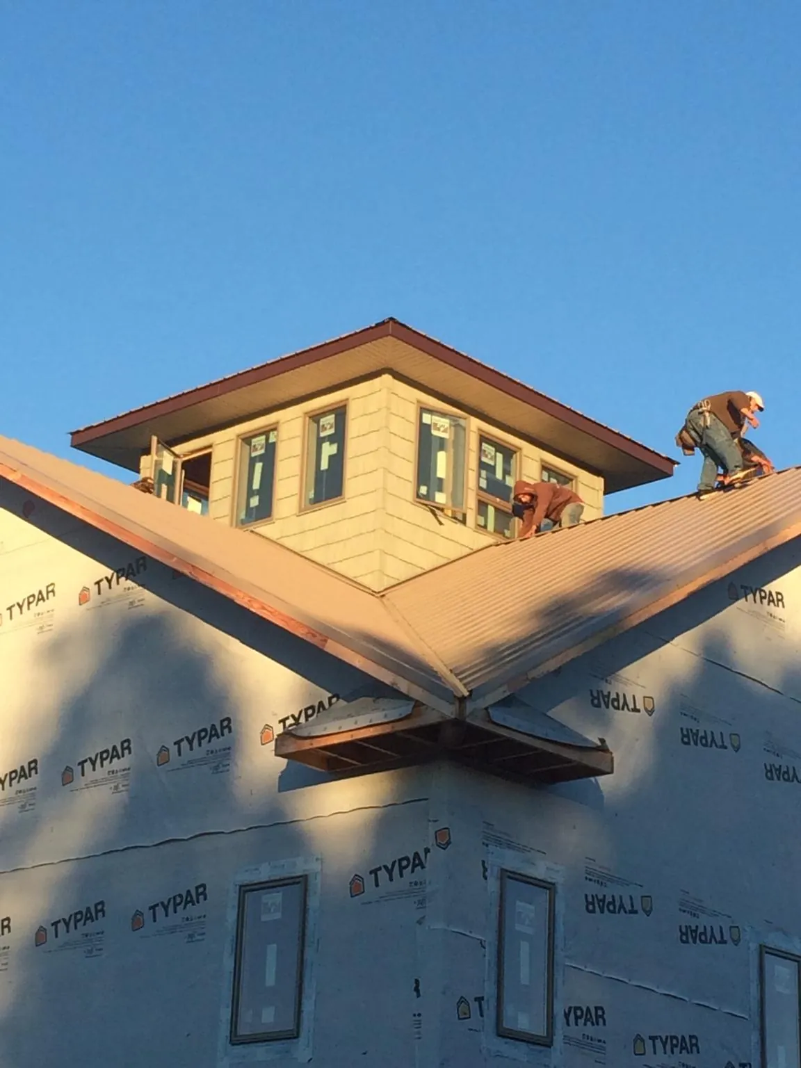 Roofers working around a rooftop cupola on a new metal roof at sunset — Roof Waterproofing in Sagle by Roofing Brothers